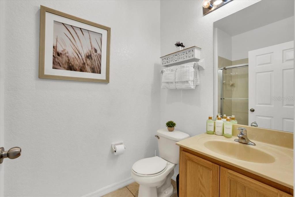 A bathroom features a wooden vanity, a white toilet, and a framed wall print — 2783 CORVETTE LANE, KISSIMMEE, FL