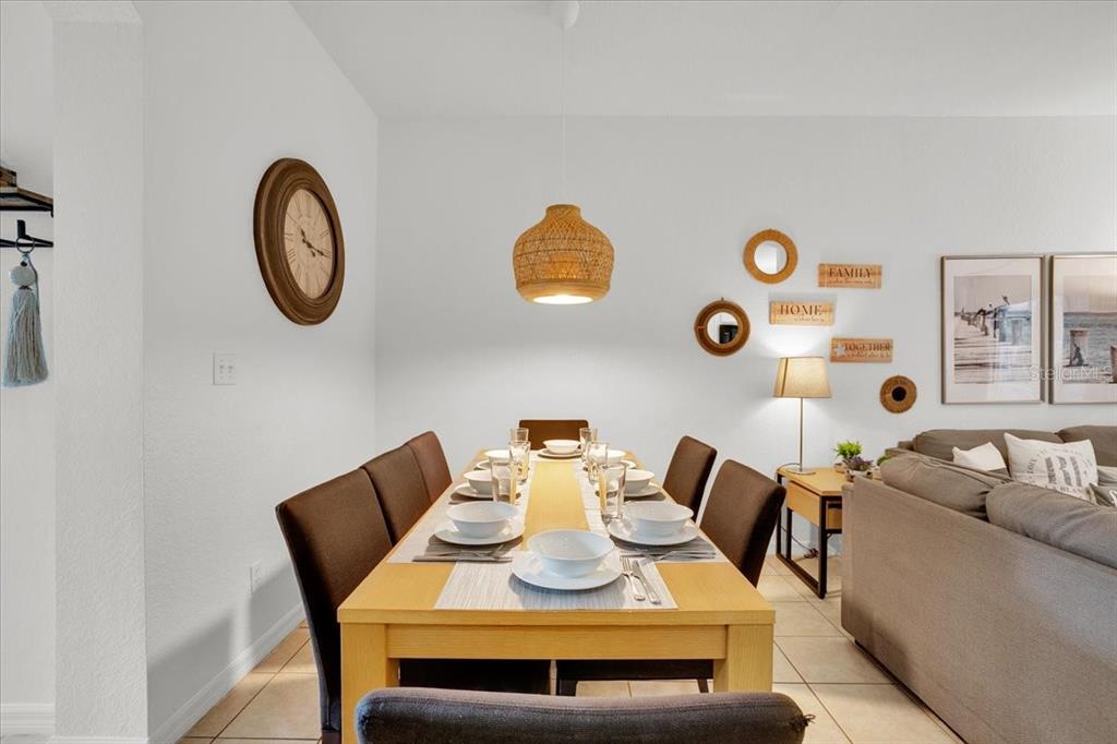 A dining room features a wooden table with six chairs, a pendant light, and wall decor — 2783 CORVETTE LANE, KISSIMMEE, FL