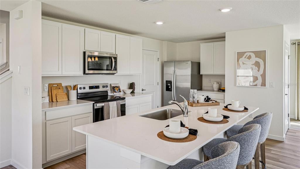 A modern kitchen features white cabinetry, stainless steel appliances, and a large central island — 2158 NE 28TH LANE, OCALA, FL