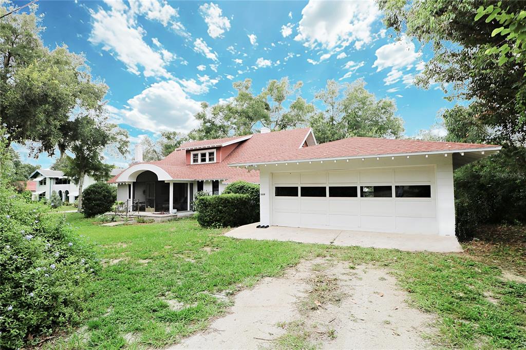 A house with a red shingled roof, a white garage, and a screened-in porch — 1109 CODY VILLA LOOP ROAD, BABSON PARK, FL