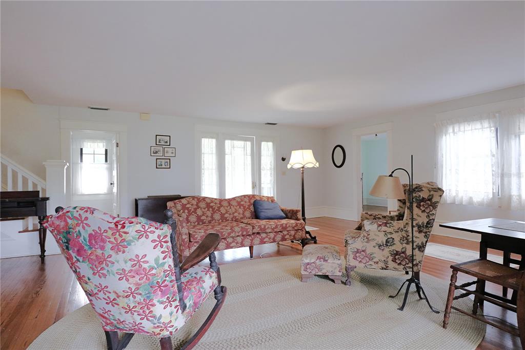 A living room features floral furniture, a braided rug, hardwood floors, and white walls — 1109 CODY VILLA LOOP ROAD, BABSON PARK, FL