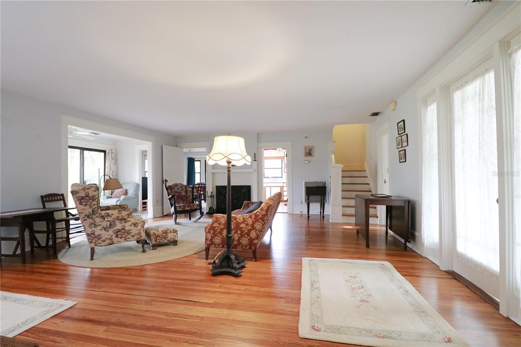 A spacious living room features hardwood floors, a fireplace, a staircase, and traditional floral furniture — 1109 CODY VILLA LOOP ROAD, BABSON PARK, FL