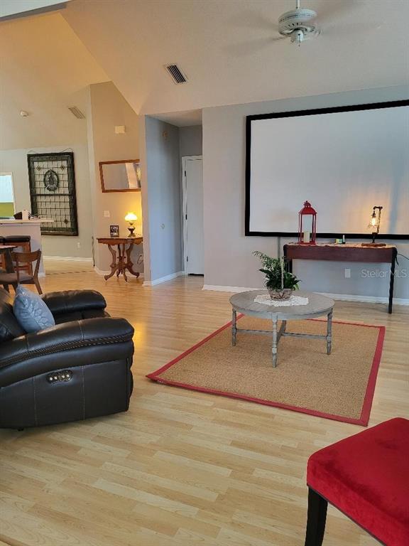 A living room features light wood flooring, a projector screen, and a round coffee table — 3709 MOLLIE LANE, SUN CITY CENTER, FL