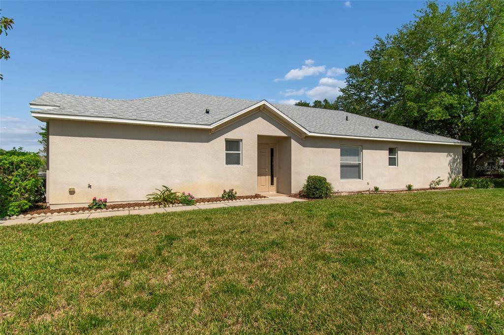A single-story house with beige stucco siding, a gray shingled roof, and a front walkway — 18630 ROLLING HILLS LOOP, HUDSON, FL