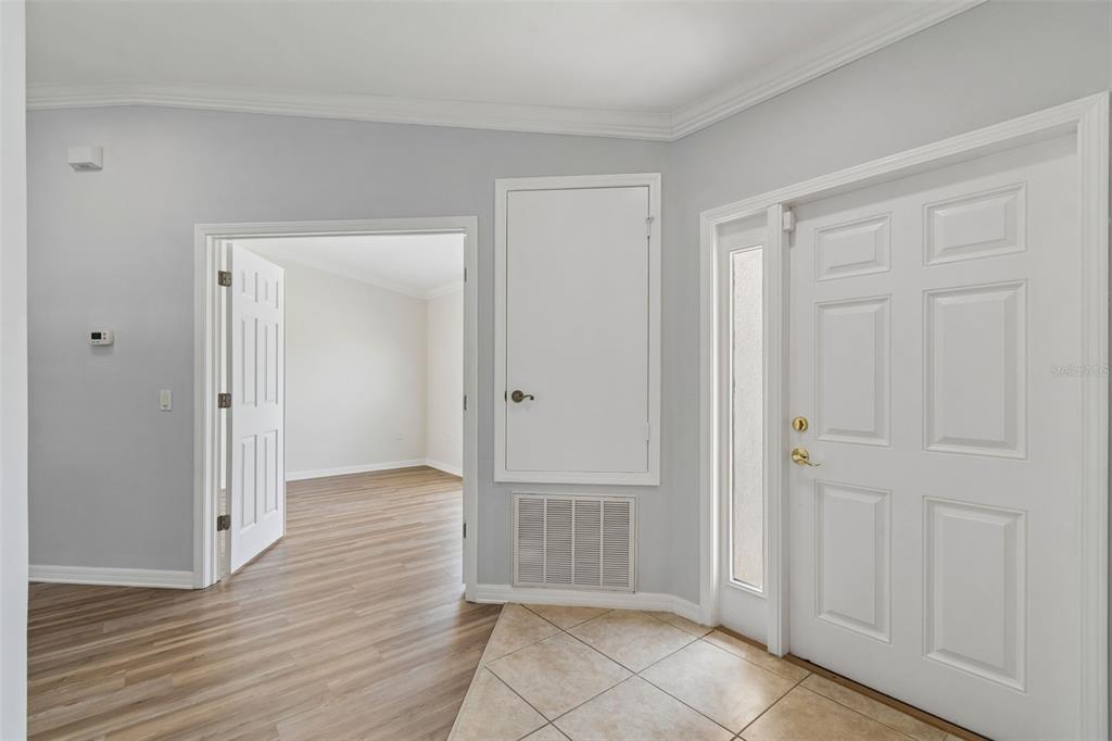 An entryway with tile flooring, a white front door, and an open doorway to another room — 18630 ROLLING HILLS LOOP, HUDSON, FL