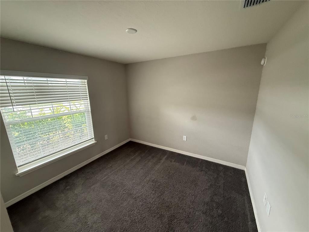 An empty bedroom features gray walls, dark carpeting, and a window with white blinds — 2586 SAN MARCO WAY, WINTER HAVEN, FL