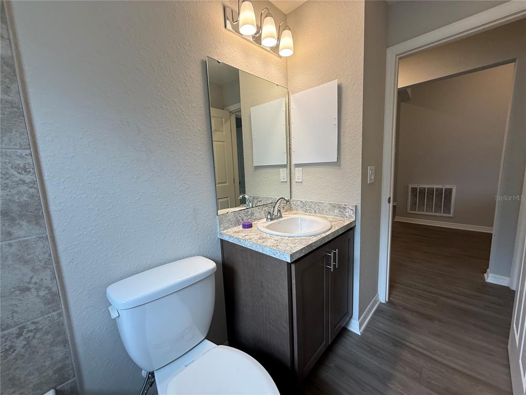 A bathroom features a dark wood vanity, a granite countertop, and a white toilet — 2586 SAN MARCO WAY, WINTER HAVEN, FL