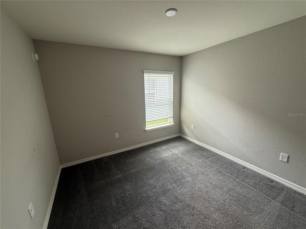 An empty bedroom features gray walls, gray carpet, and a single window with white blinds — 2586 SAN MARCO WAY, WINTER HAVEN, FL