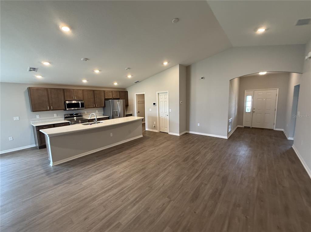 An open-concept kitchen features a large island, dark wood cabinetry, and light wood-look flooring — 2586 SAN MARCO WAY, WINTER HAVEN, FL