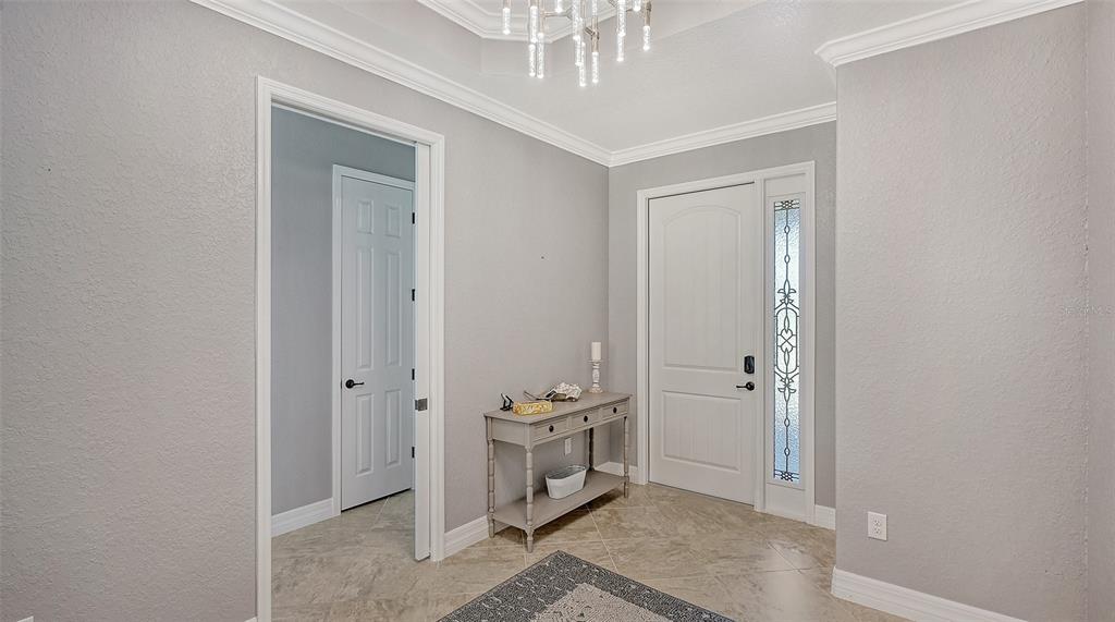 An entryway features light gray walls, tile flooring, a console table, and a front door — 6137 CESSNA RUN, BRADENTON, FL