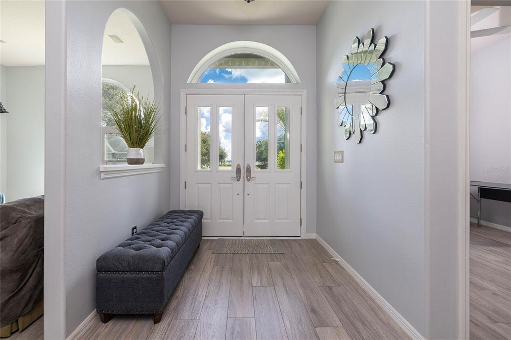 A bright entryway features a tufted gray bench, light wood flooring, and double front doors — 3009 KEY HARBOR DRIVE, SAFETY HARBOR, FL
