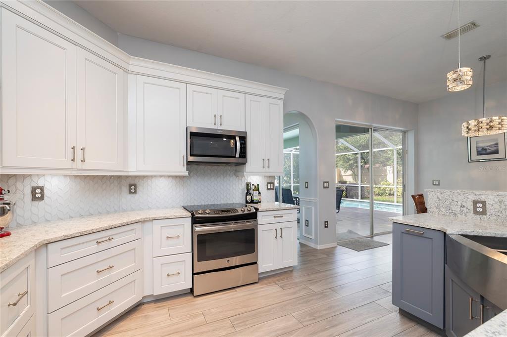 A kitchen features white cabinets, stainless steel appliances, granite countertops, and a view of a pool — 3009 KEY HARBOR DRIVE, SAFETY HARBOR, FL