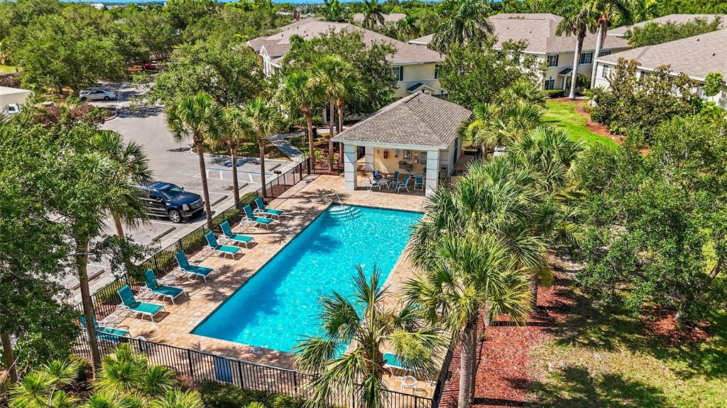 An aerial view shows a rectangular swimming pool with lounge chairs and a covered pavilion — 220 CAPE HARBOUR LOOP Unit 101, BRADENTON, FL