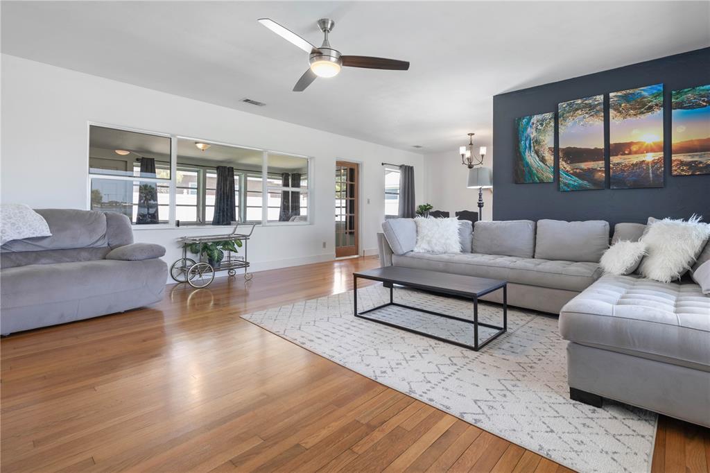 A living room features hardwood floors, a gray sectional sofa, and a dark accent wall — 504 RIVERSIDE DRIVE, HOLLY HILL, FL