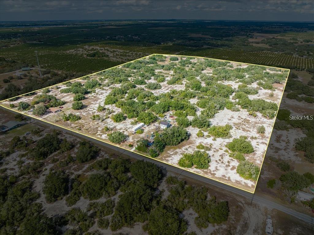 An aerial view shows a large, rectangular plot of land with scattered trees and structures — LIBBY RD, BABSON PARK, FL
