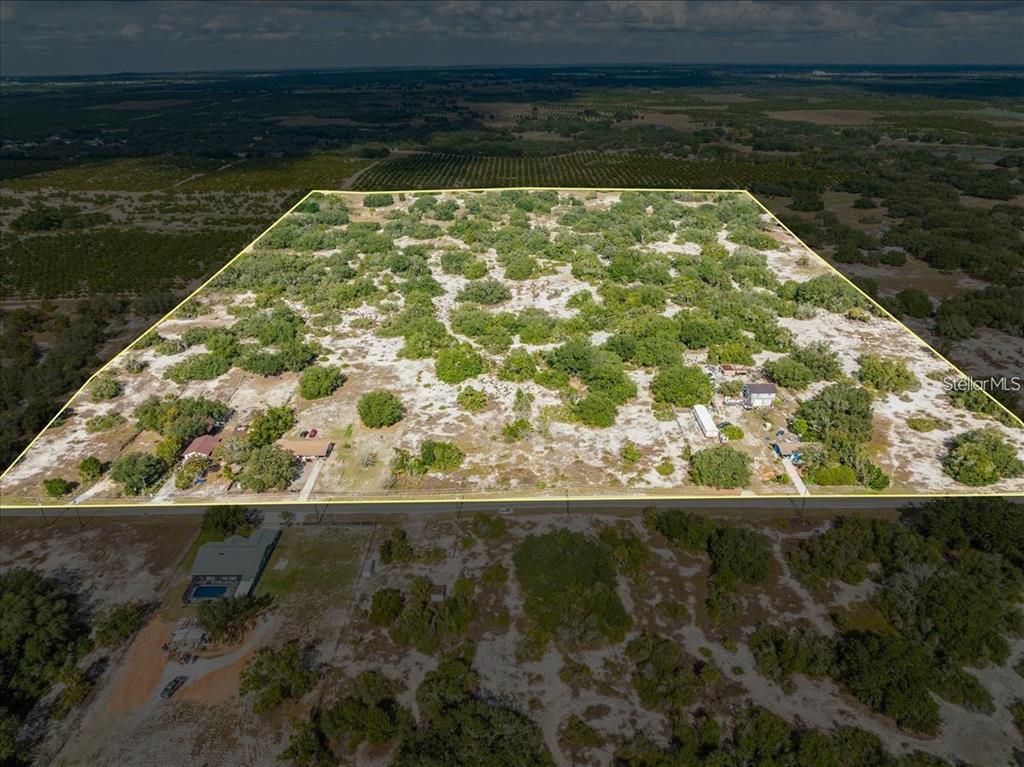 An aerial view shows a large, rectangular plot of land with scattered trees and structures — LIBBY RD, BABSON PARK, FL