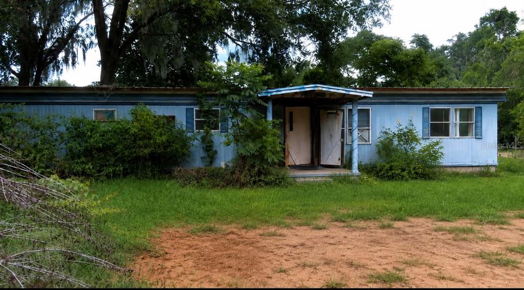 A blue single-wide mobile home with a small front porch sits on a grassy lot — 17990 SE 51ST STREET, OCKLAWAHA, FL