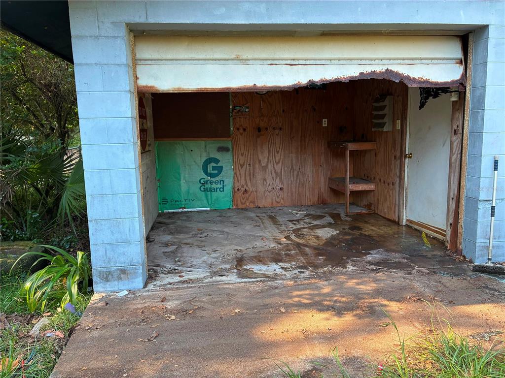 An open-front garage with concrete block walls, a plywood interior, and a damaged metal header — 17990 SE 51ST STREET, OCKLAWAHA, FL