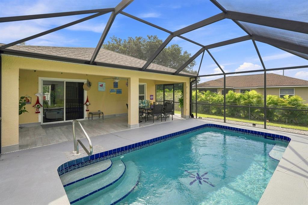 A screened-in patio features a swimming pool with steps and a covered dining area — 7570 CROCK AVENUE, NORTH PORT, FL