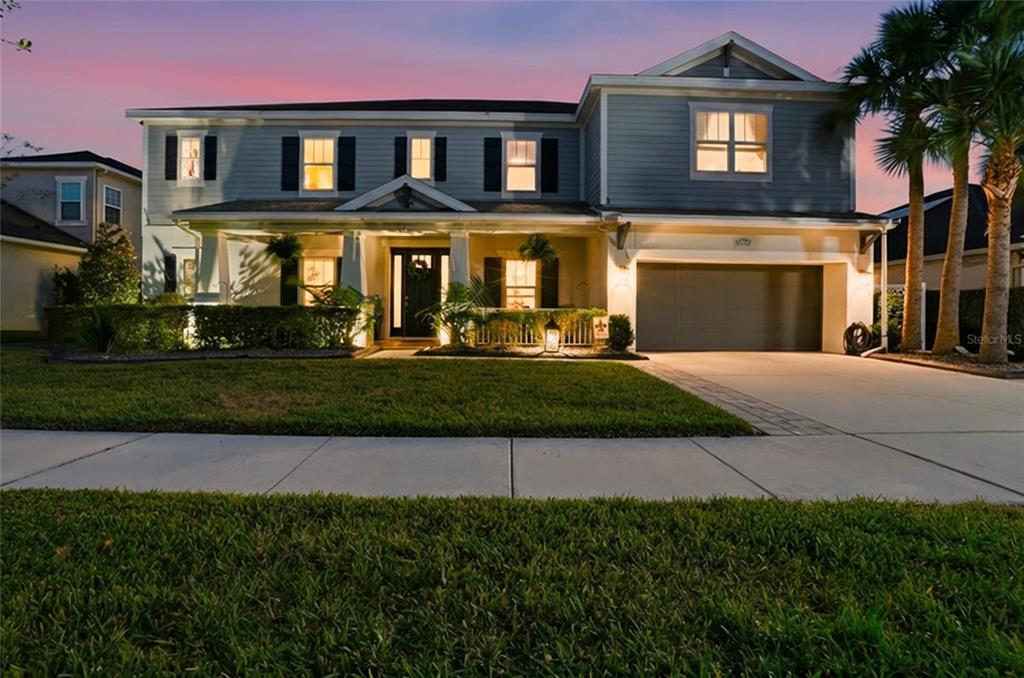 A two-story house with gray siding, a front porch, and an attached garage at dusk — 33564 WILLOW POINT CT, WESLEY CHAPEL, FL