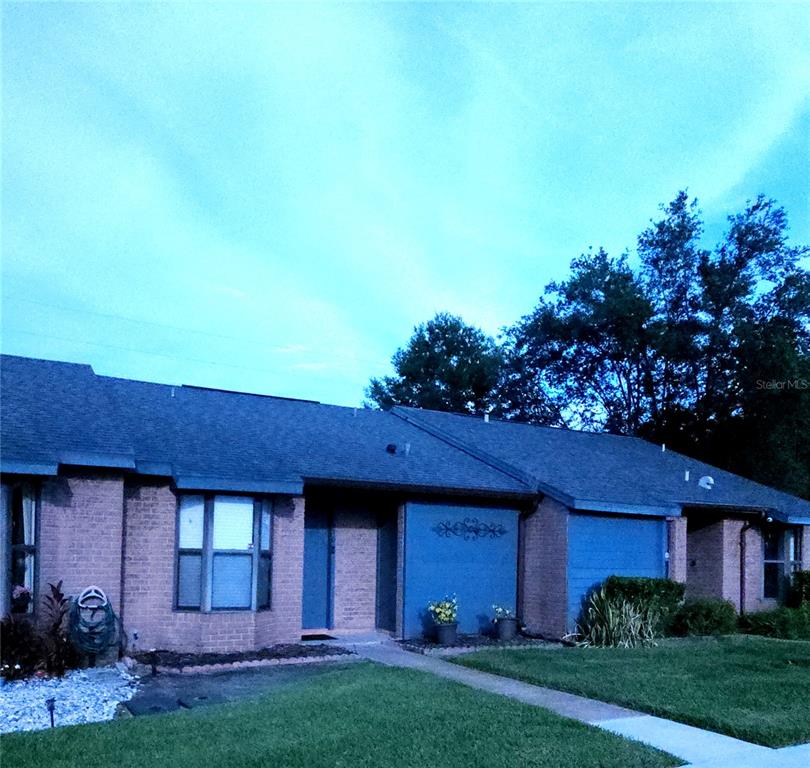 A single-story brick house with a blue-painted section and a front walkway at dusk — 2510 KING OAK CIRCLE, ST CLOUD, FL