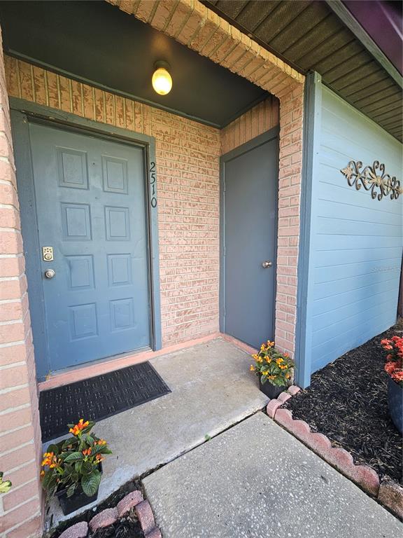 A blue front door and a smaller utility door are set into a brick exterior wall — 2510 KING OAK CIRCLE, ST CLOUD, FL
