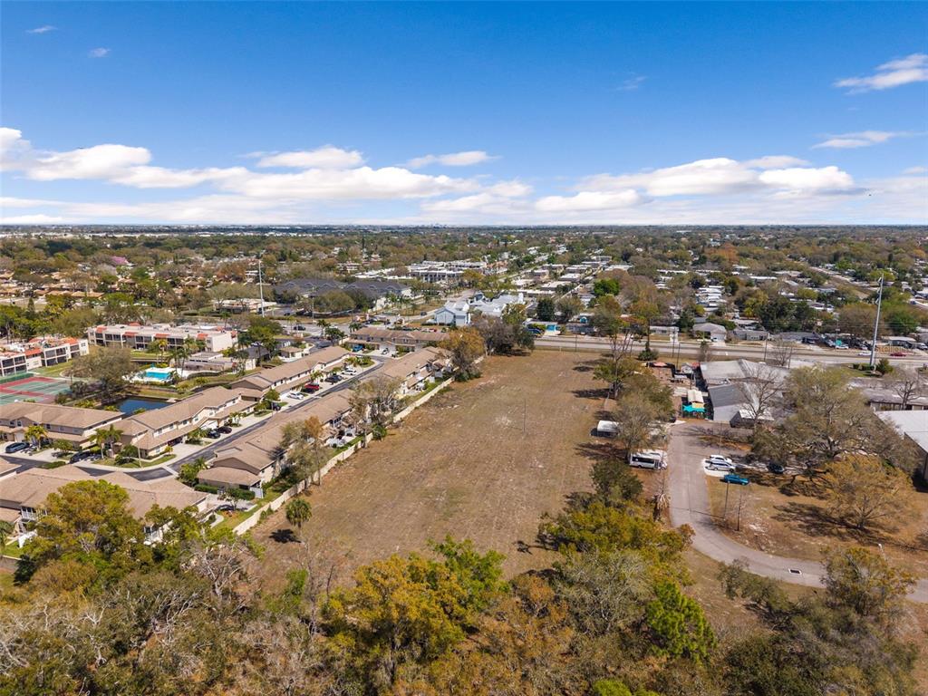 An aerial view shows a large, vacant grassy lot adjacent to a residential townhouse complex — 9530 STARKEY ROAD, SEMINOLE, FL
