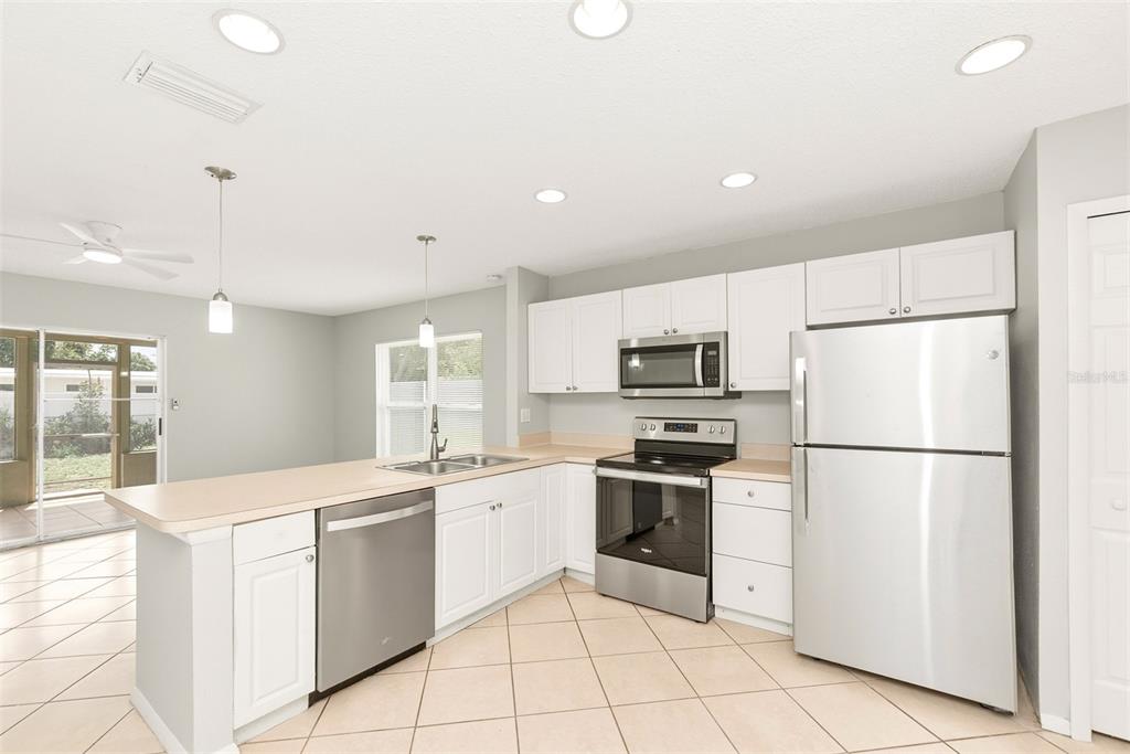 A kitchen with white cabinets, stainless steel appliances, a breakfast bar, and light tile flooring — 1215 39TH STREET W, BRADENTON, FL