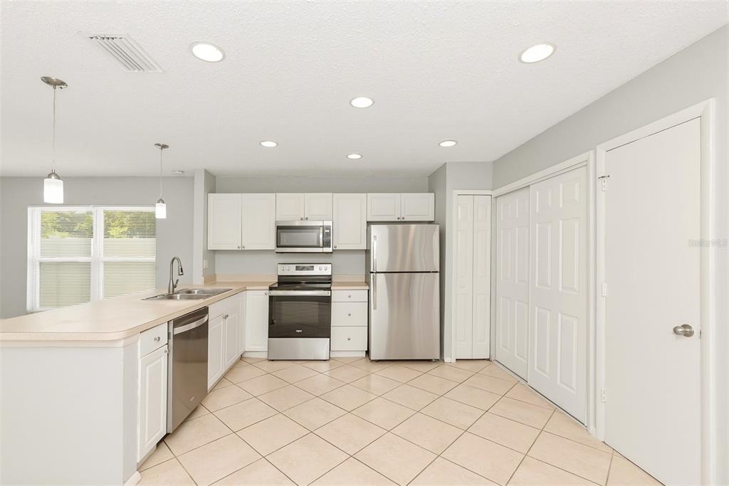 A kitchen with white cabinets, stainless steel appliances, a peninsula, and light-colored tile flooring — 1215 39TH STREET W, BRADENTON, FL
