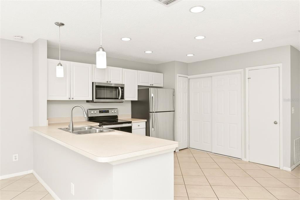 A kitchen with white cabinets, stainless steel appliances, a breakfast bar, and light-colored tile flooring — 1215 39TH STREET W, BRADENTON, FL