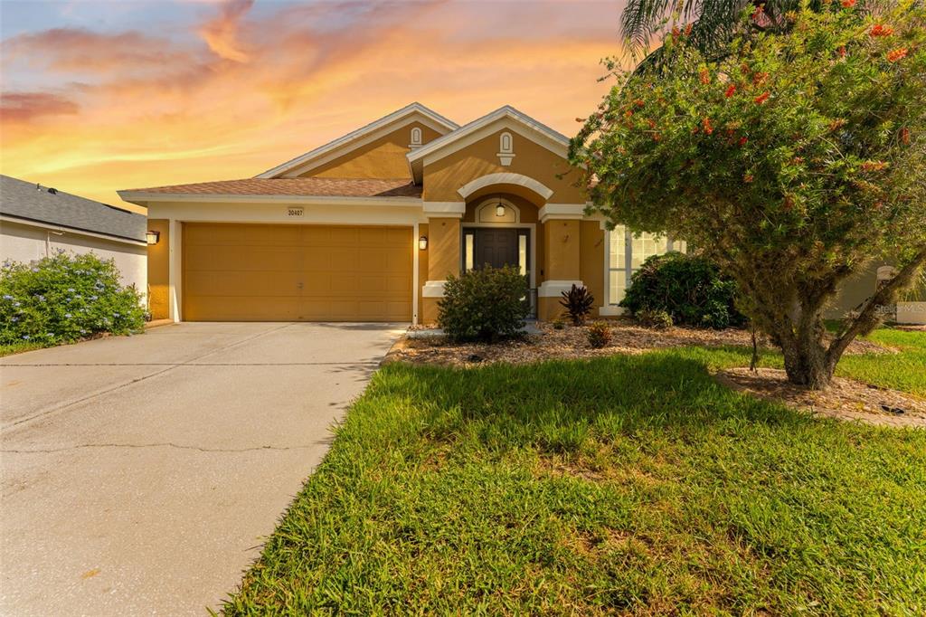 A single-story house with a yellow stucco exterior, a two-car garage, and a front lawn — 30407 STAPLETON STREET, WESLEY CHAPEL, FL