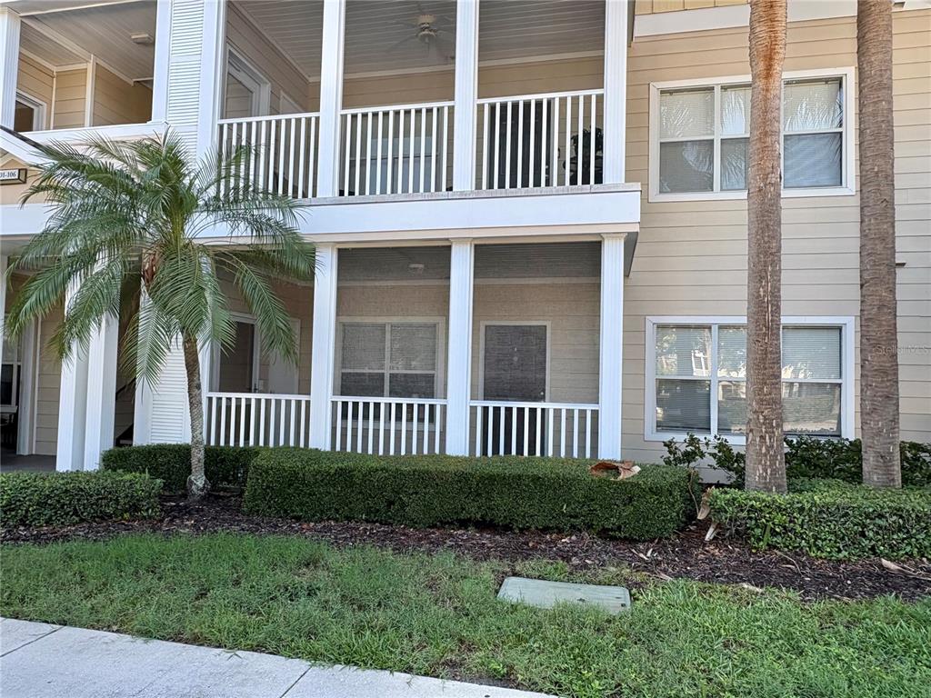 The exterior of a two-story apartment building features screened-in balconies and tan siding — 4802 51ST STREET W UNIT 102, BRADENTON, FL
