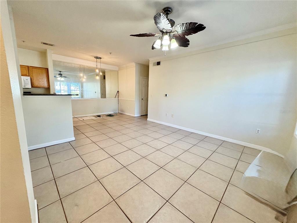 An open-concept living and dining area features light-colored tile flooring and a ceiling fan — 4802 51ST STREET W UNIT 102, BRADENTON, FL