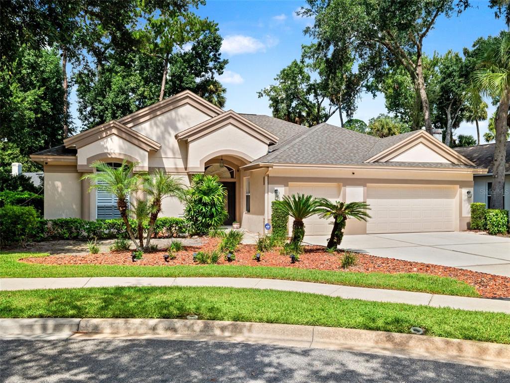 A single-story house with a beige stucco exterior, a multi-car garage, and a landscaped front yard — 5325 LAKE BLUFF TERRACE, SANFORD, FL