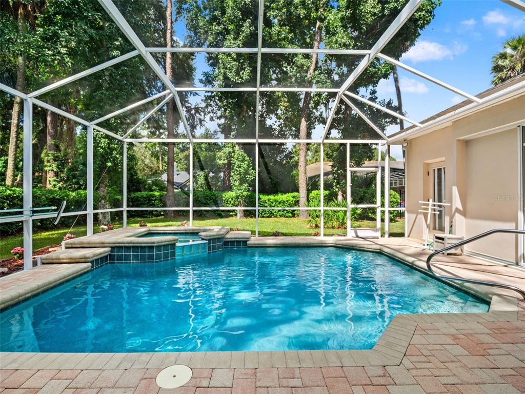 A screened-in swimming pool and spa with a brick paver deck and surrounding trees — 5325 LAKE BLUFF TERRACE, SANFORD, FL