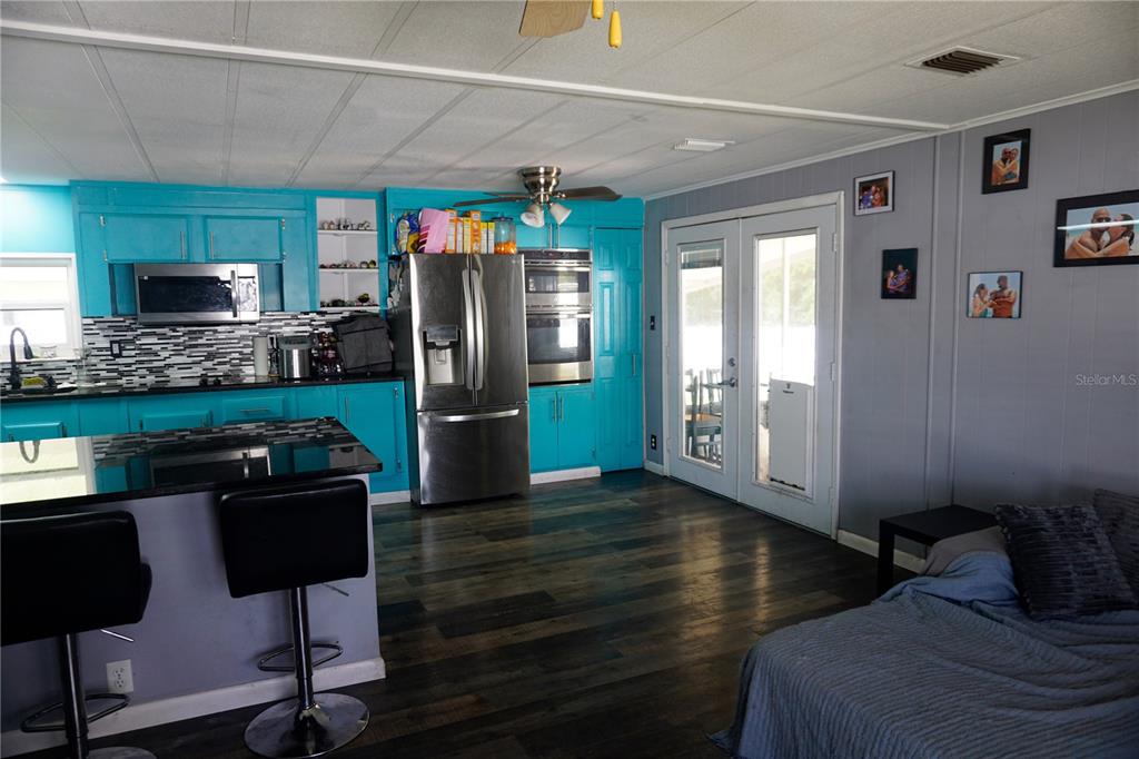A kitchen with bright blue cabinets, stainless steel appliances, and dark wood-look flooring — 143 FLORENCE BOULEVARD, DEBARY, FL