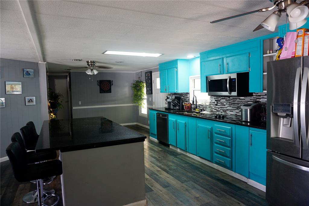 A kitchen features bright blue cabinets, a black island, and dark wood-look flooring — 143 FLORENCE BOULEVARD, DEBARY, FL