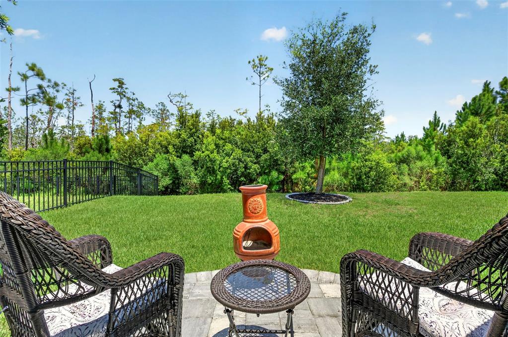 Two wicker chairs and a small table sit on a patio overlooking a grassy yard — 106 NIGHTHAWK LANE, PALM COAST, FL