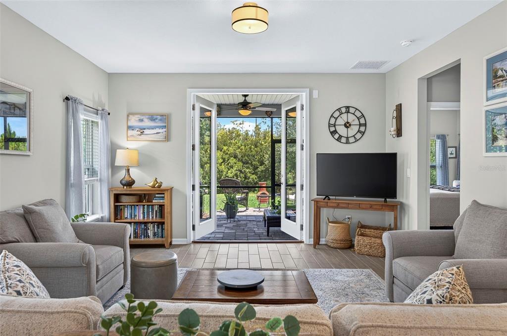 A living room with gray furniture, a television, and French doors opening to a patio — 106 NIGHTHAWK LANE, PALM COAST, FL