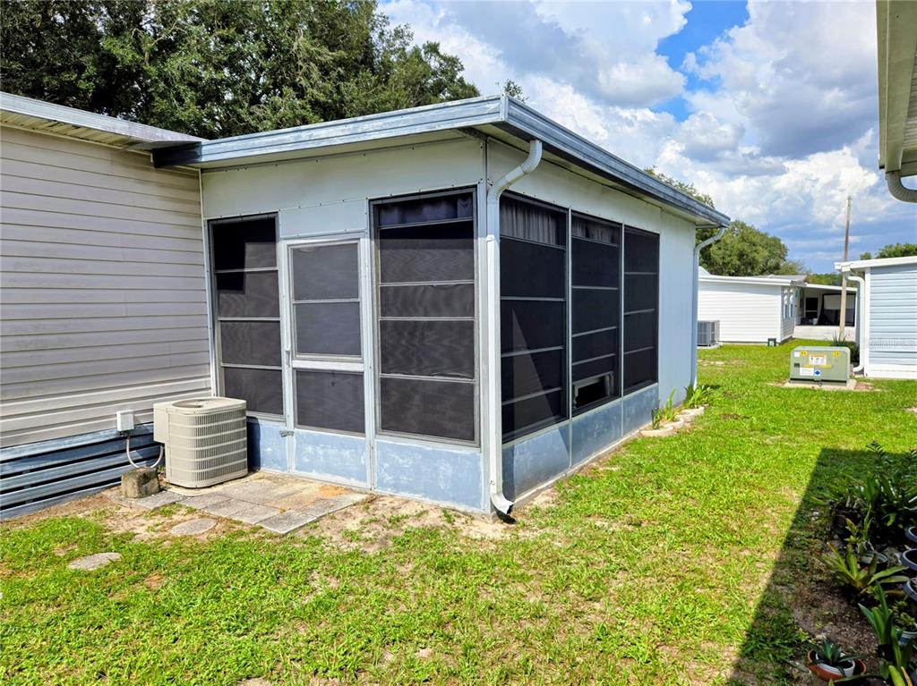 A screened-in porch is attached to the side of a light-colored mobile home — 6336 WEALTHY LANE, ZEPHYRHILLS, FL