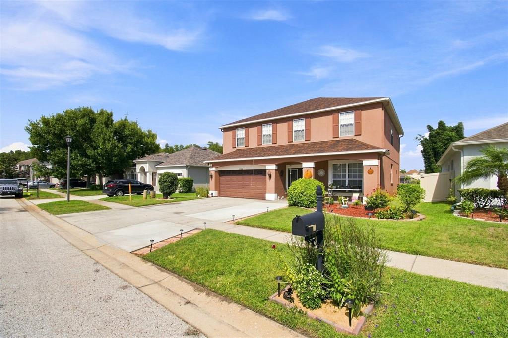 A two-story suburban house with a brown stucco exterior, a two-car garage, and a mailbox — 17919 AYRSHIRE BOULEVARD, LAND O LAKES, FL