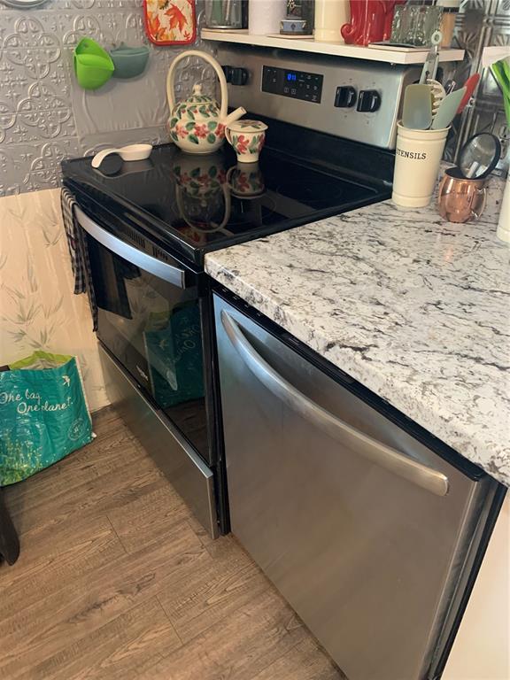 A kitchen features a stainless steel oven and dishwasher with granite countertops and tiled walls — 10456 PEACEFUL DRIVE, LARGO, FL