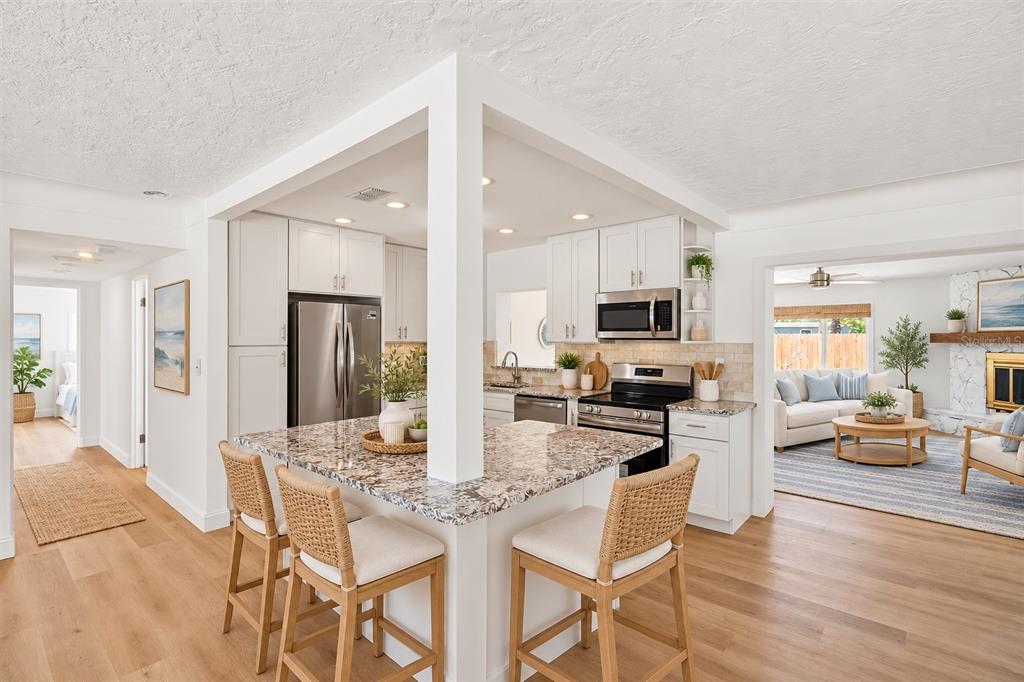 An empty living room with white walls, light wood-look flooring, and a front entry door — 7919 CAUSEWAY BOULEVARD S, ST PETERSBURG, FL