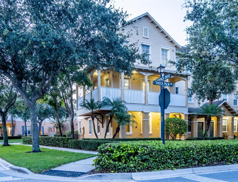 A two-story house with a wrap-around balcony stands at a street corner with landscaping — 103 E THATCH PALM CIRCLE, JUPITER, FL