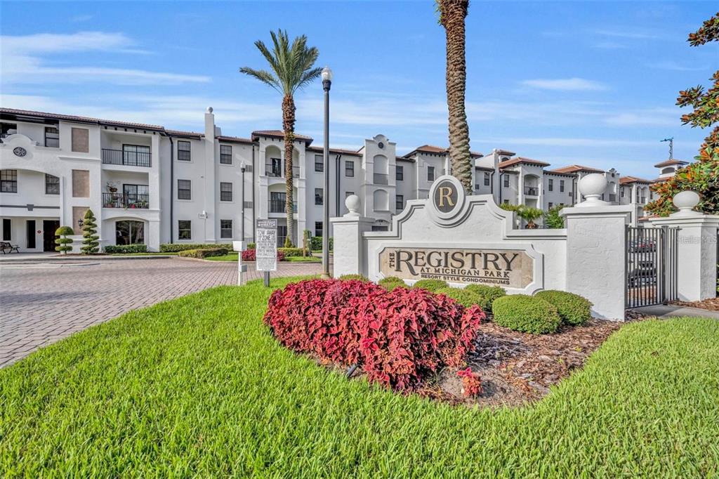 The exterior of a multi-story apartment complex features a prominent monument sign in the foreground — 5550 E MICHIGAN STREET UNIT 3216, ORLANDO, FL