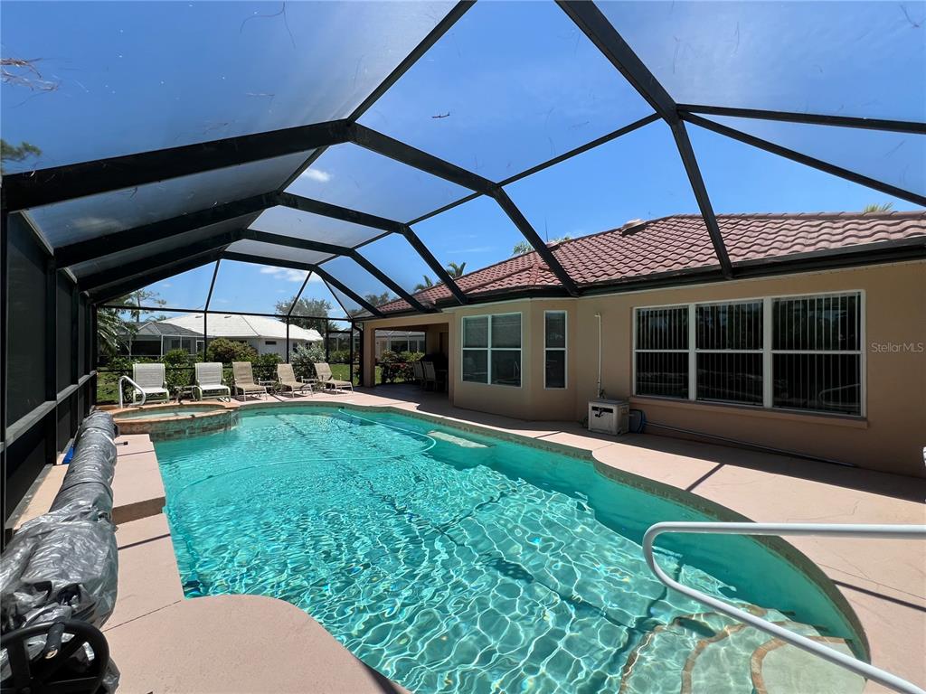 A swimming pool with a spa is enclosed by a screened lanai behind a house — 4005 BIG PASS LANE, PUNTA GORDA, FL