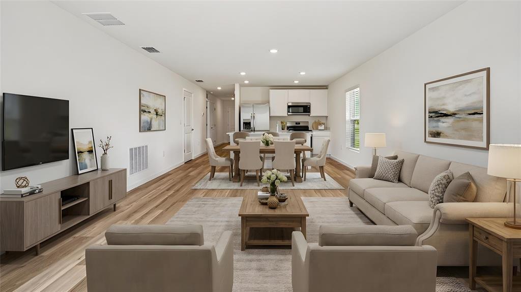 An open-concept living and dining area features light wood flooring and neutral-toned furniture — 3095 GREY MOSS DRIVE, ST CLOUD, FL