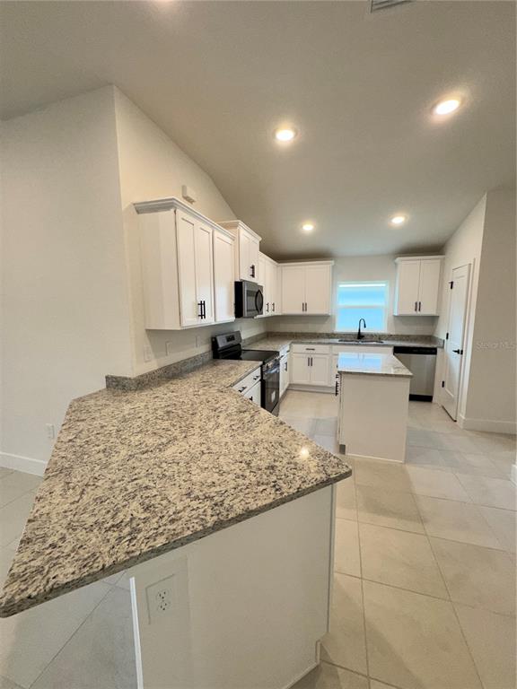 A kitchen with white cabinets, granite countertops, a center island, and light-colored tile flooring — 2675 AVERLAND LOOP, NORTH PORT, FL