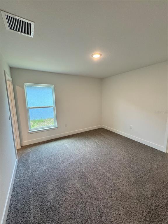 An empty bedroom features gray carpet, white walls, a single window, and a ceiling vent — 2675 AVERLAND LOOP, NORTH PORT, FL