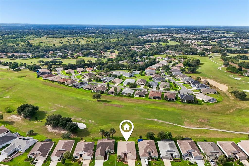 An aerial view shows a residential neighborhood with houses bordering a golf course — 27143 ROANOKE DRIVE, LEESBURG, FL